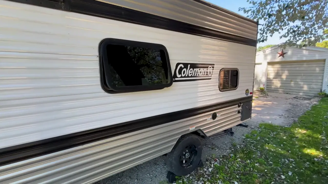 Side view of our Coleman travel trailer showing the Coleman logo, windows, and wheels