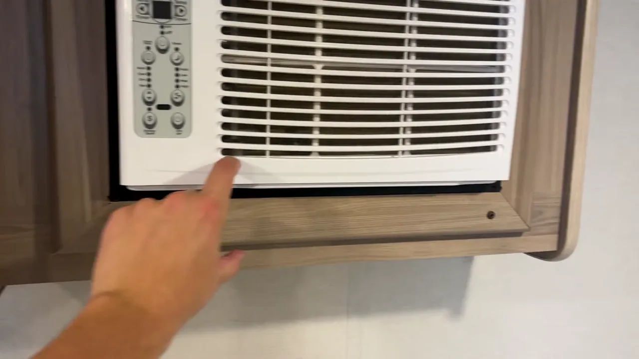 Pointing to the bottom front edge of the Coleman 17B AC unit where water drips inside