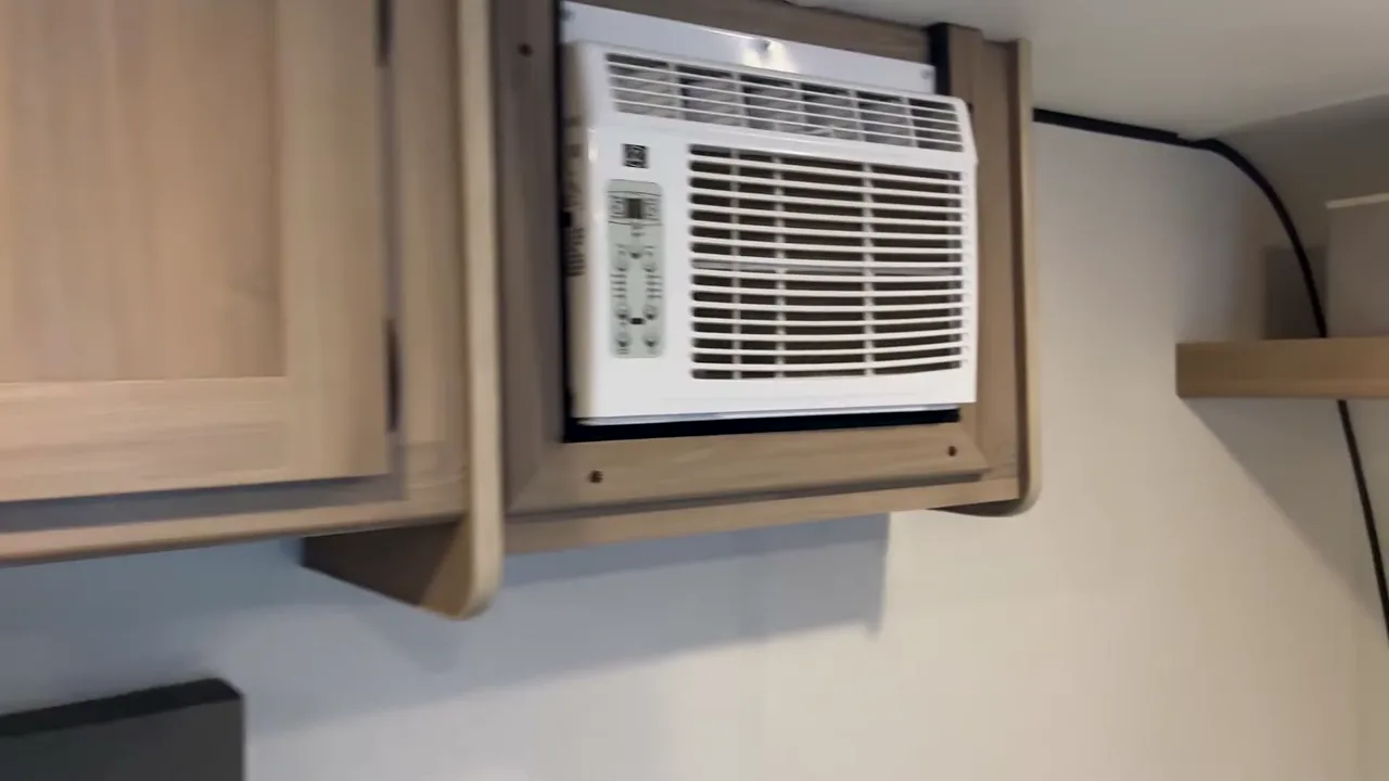 The wall-mounted AC unit inside a Coleman 17B, built into a cabinet near the bed
