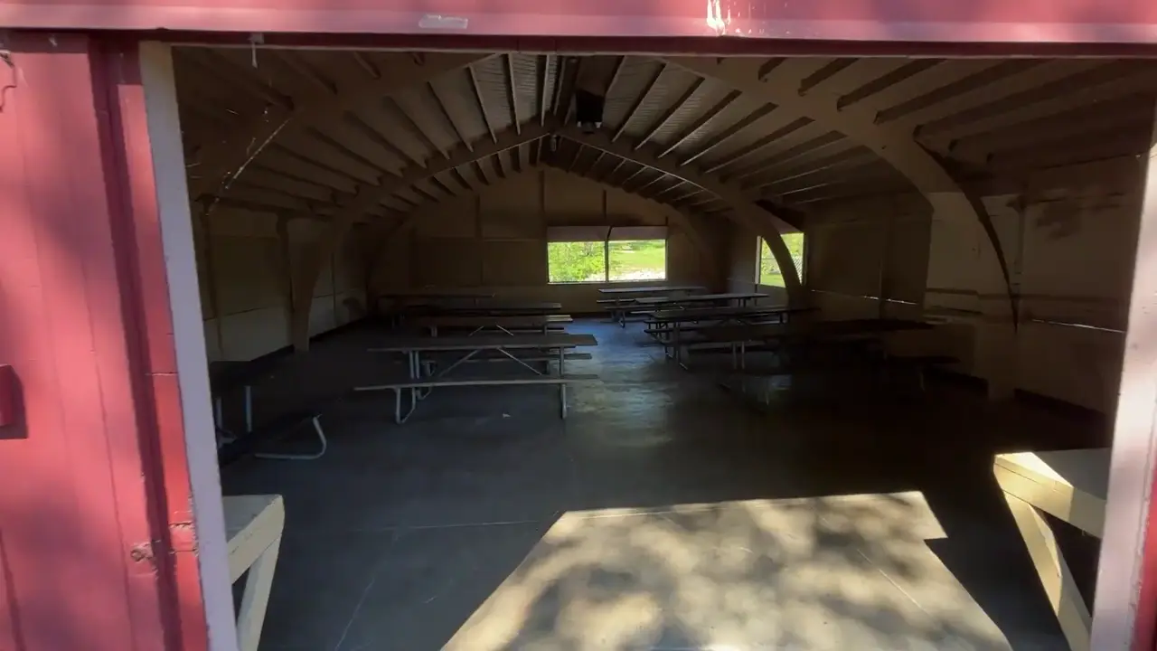 Inside the Fontana Mill Shelter House with rows of picnic tables and open side panels