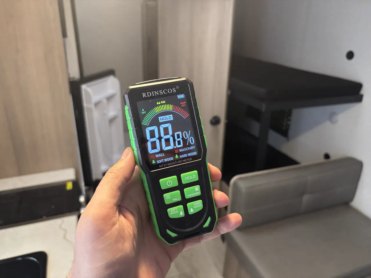 Holding an RDINSCOS MT37 pinless moisture meter inside our Coleman 17B, with its dry, risk, and wet scale on the screen